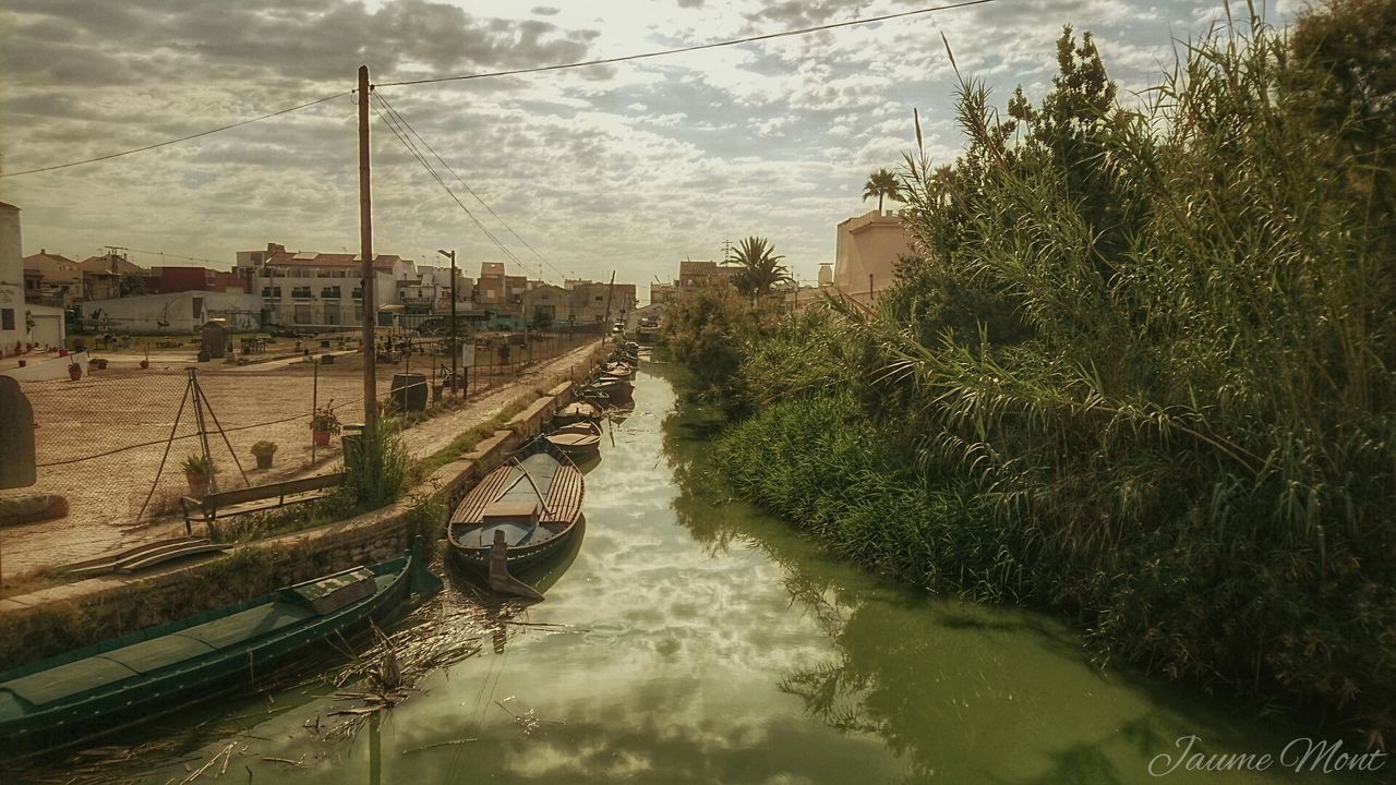 VIEW OF BOATS MOORED IN RIVER AGAINST CLOUDY SKY