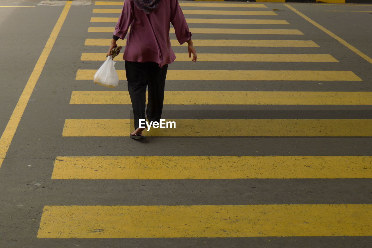 Low section of woman walking on zebra crossing