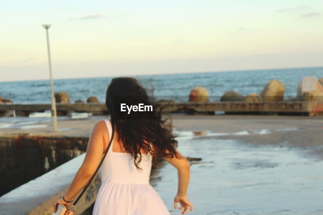 REAR VIEW OF WOMAN AGAINST SEA