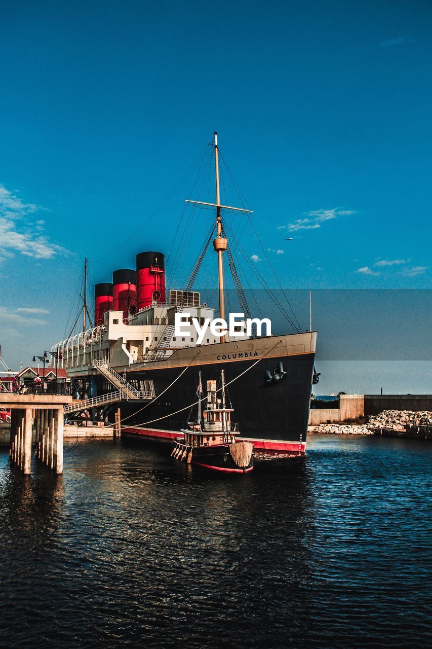 Boat moored at harbor against blue sky