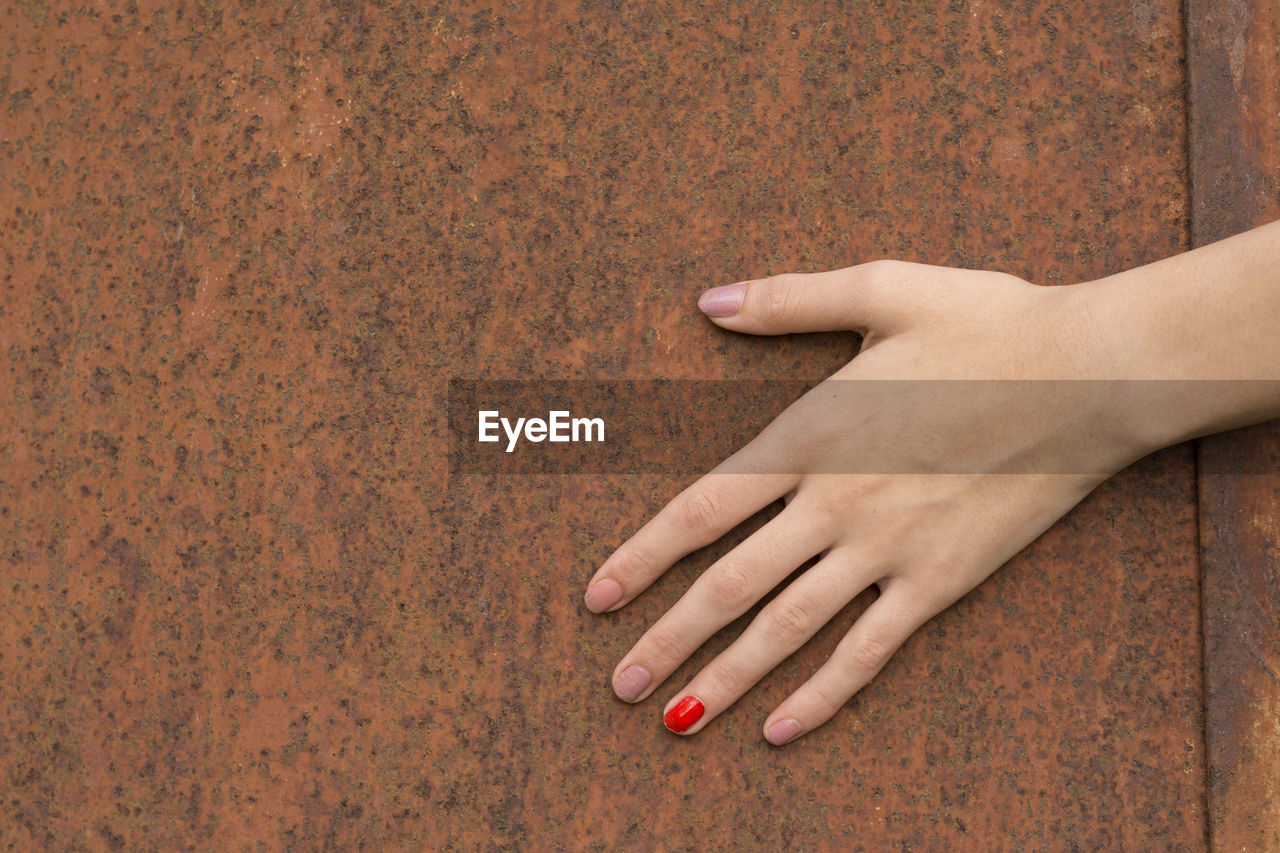 Cropped hand of woman touching rusty metal