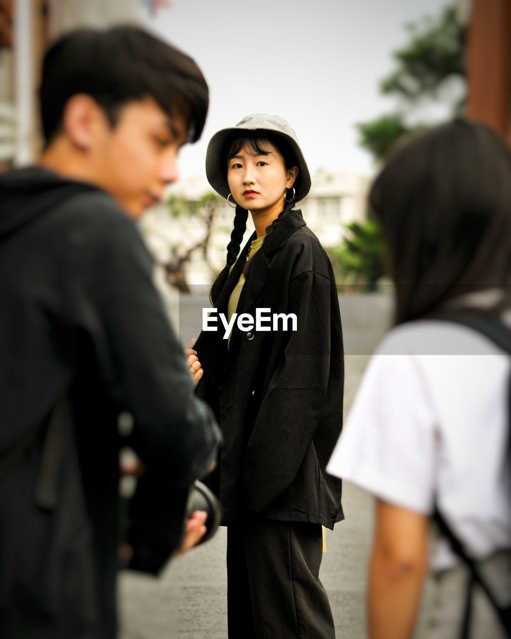 SIDE VIEW OF A YOUNG MAN WITH HAT STANDING AGAINST PEOPLE