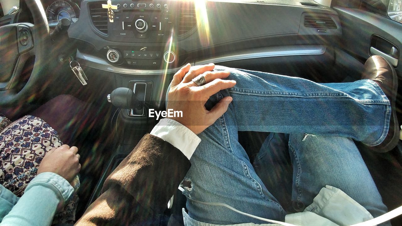 MIDSECTION OF MAN SITTING BY CAR