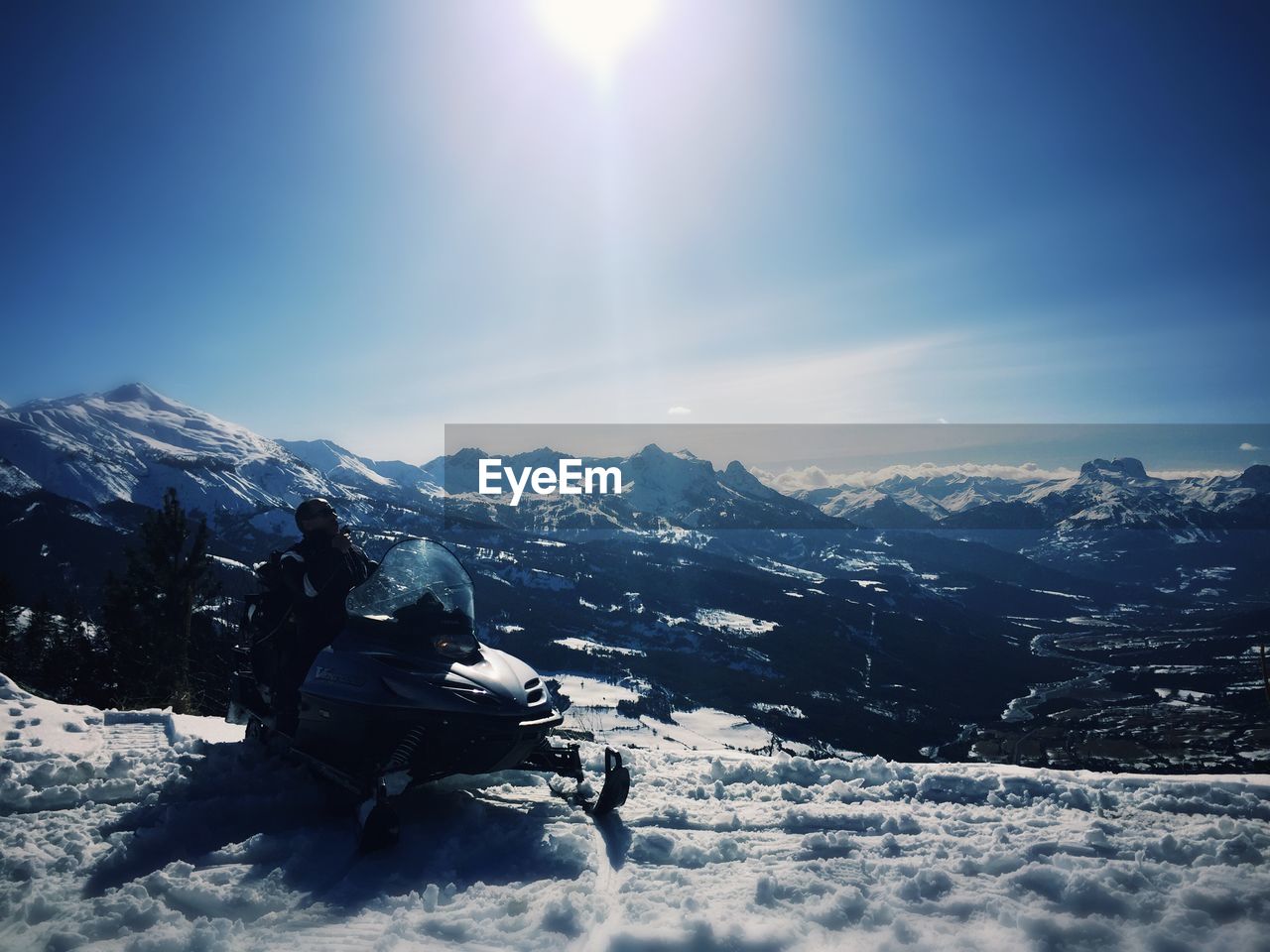 Man snowmobiling on snowcapped mountains against sky