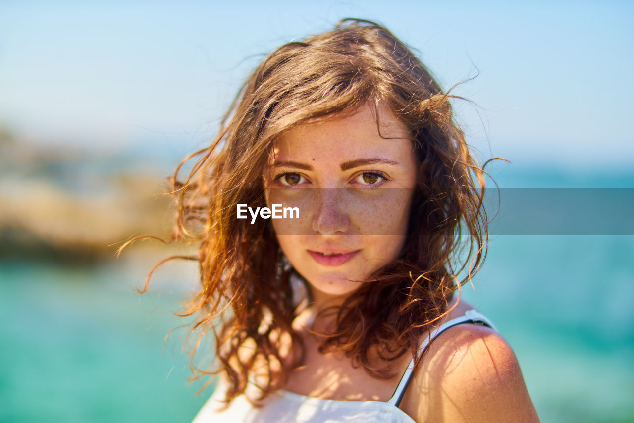 Portrait of young woman against sea