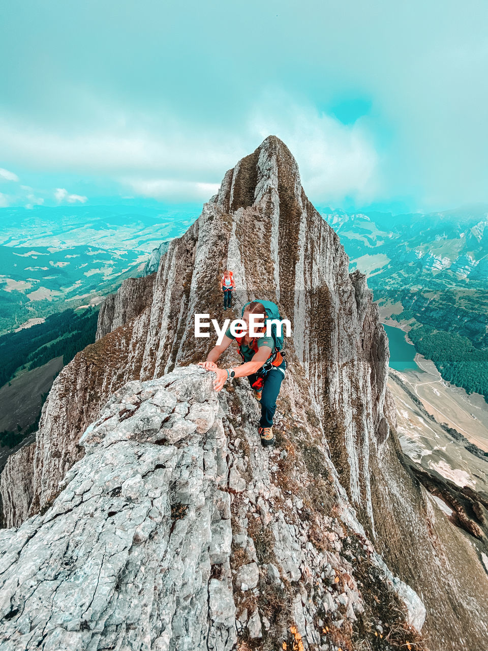 Two female climbers on narrow ridge above alpine lake in swiss alps