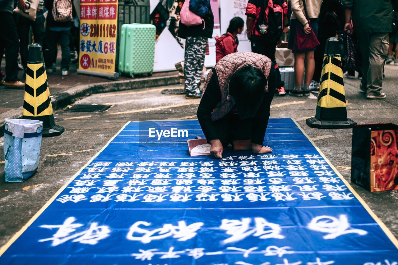 Man writing chinese script on textile with white powder on street