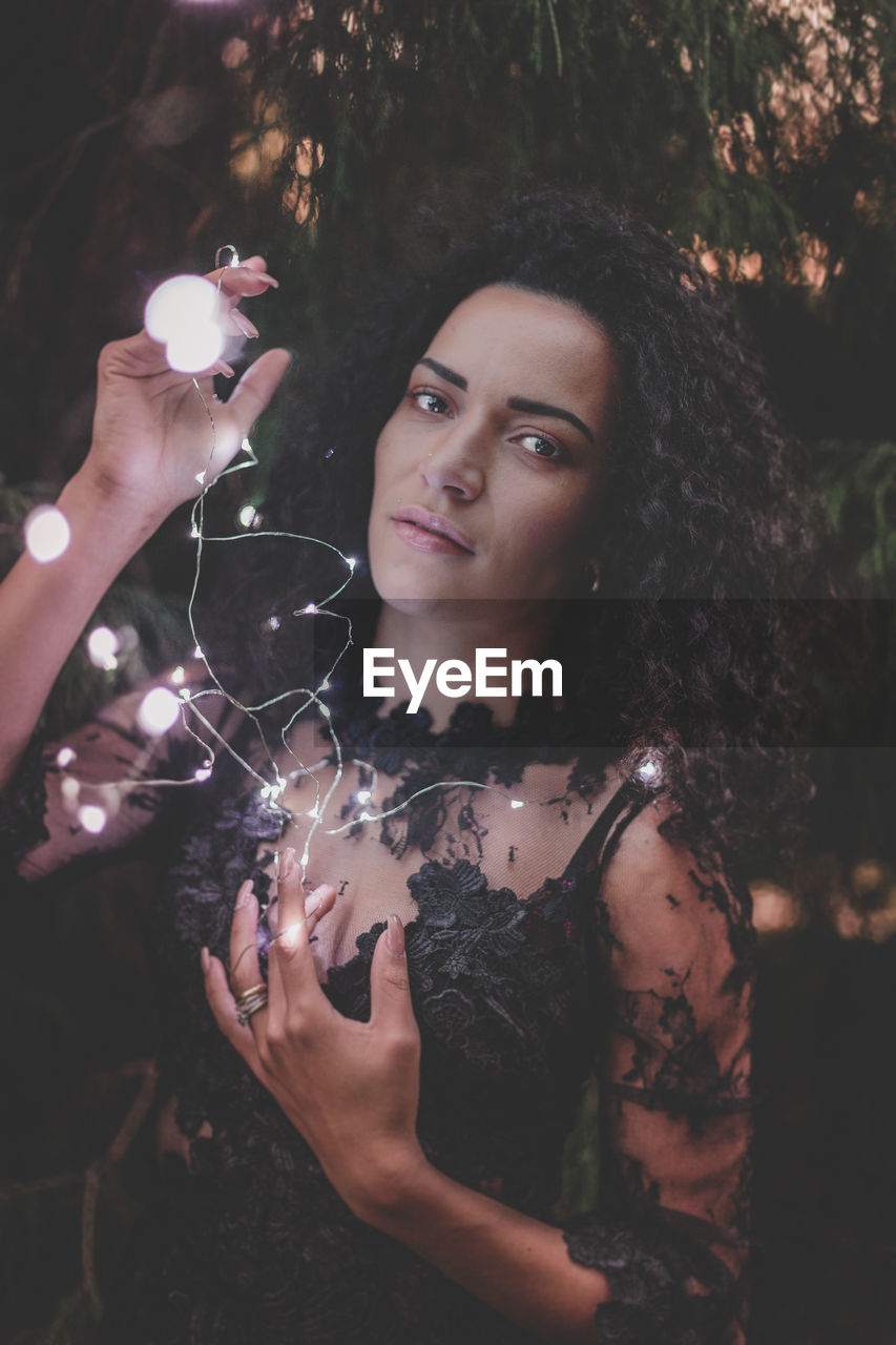 Close-up portrait of beautiful woman holding illuminated lights