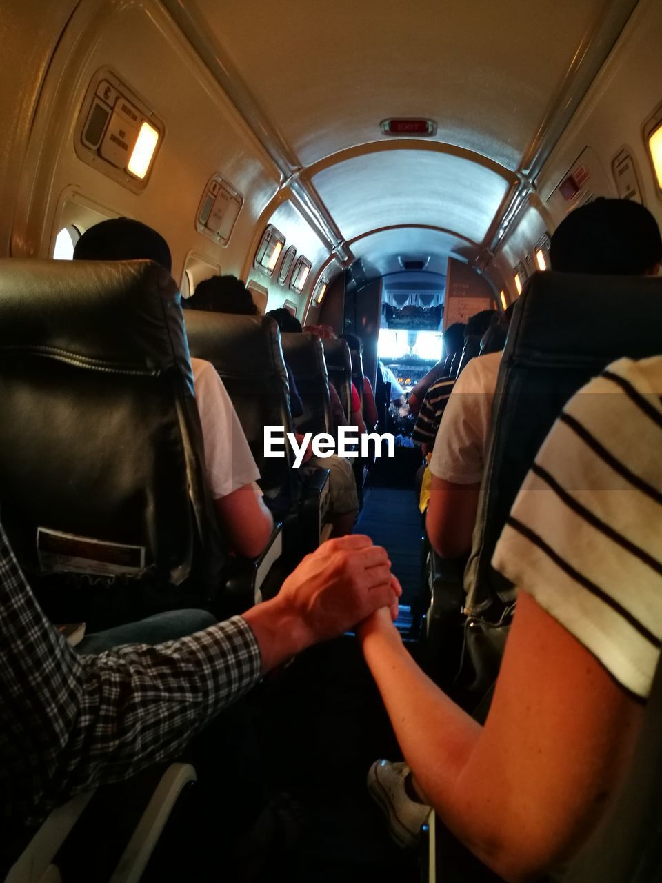 Couple with holding hands sitting in airplane