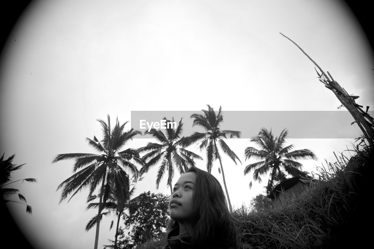 WOMAN WITH PALM TREE AGAINST SKY