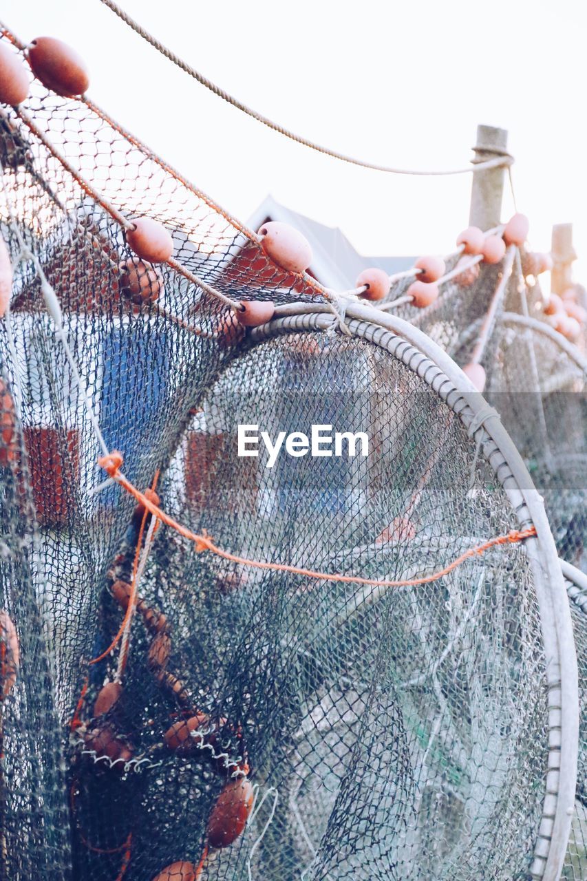 Close-up of fishing net hanging at harbor during sunset