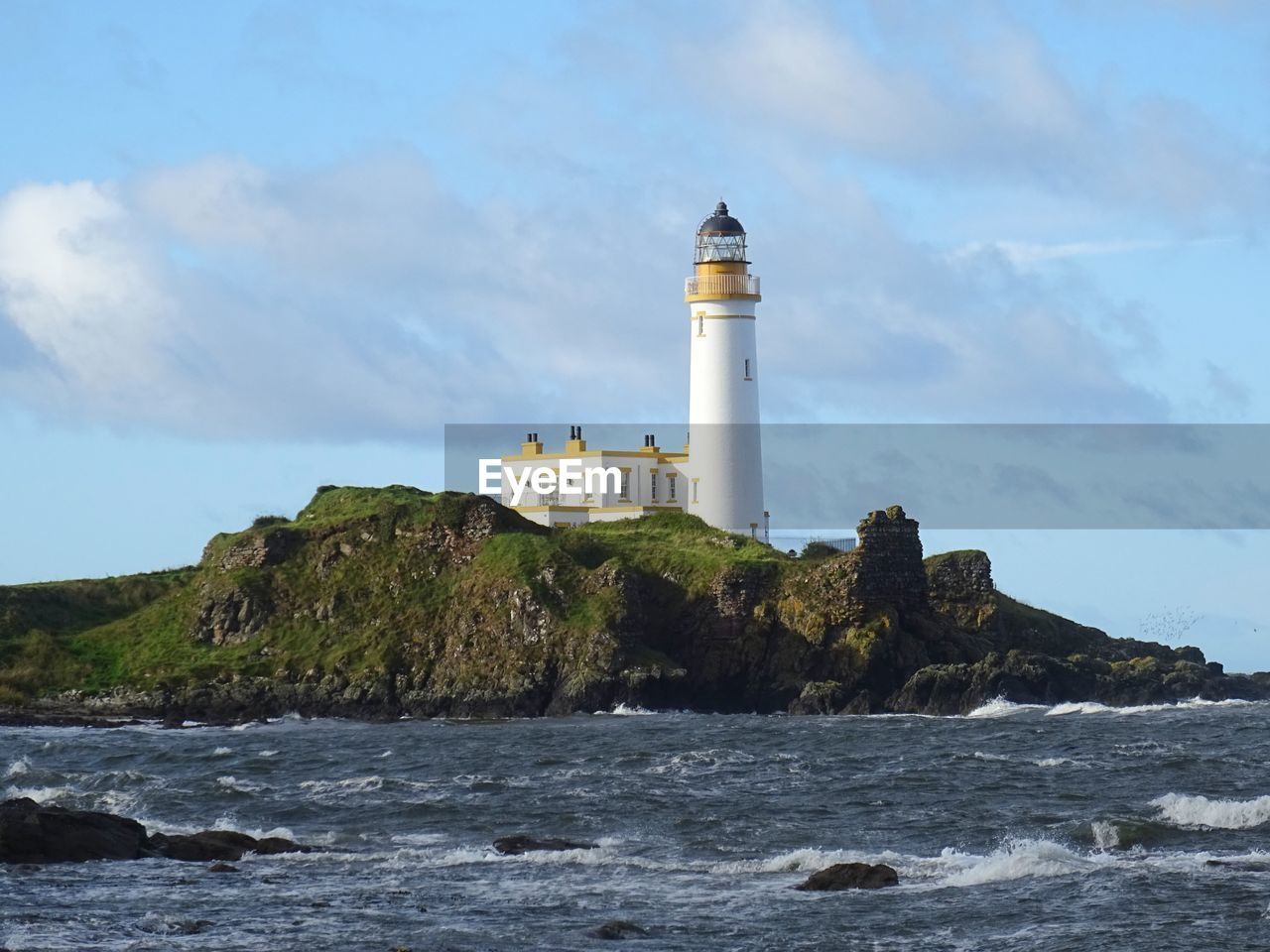 Lighthouse by sea against sky