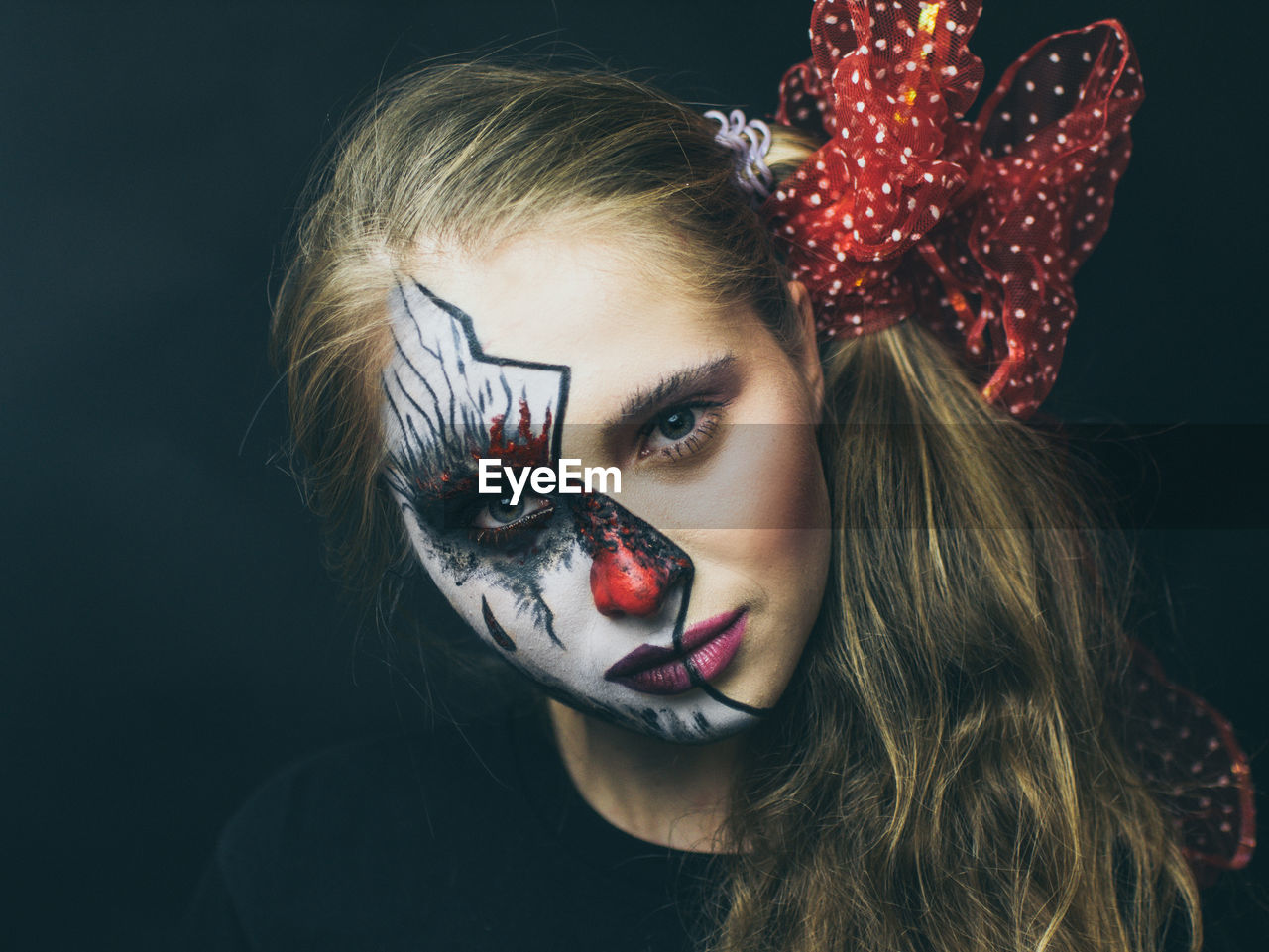 Close-up portrait of woman with painted face against black background