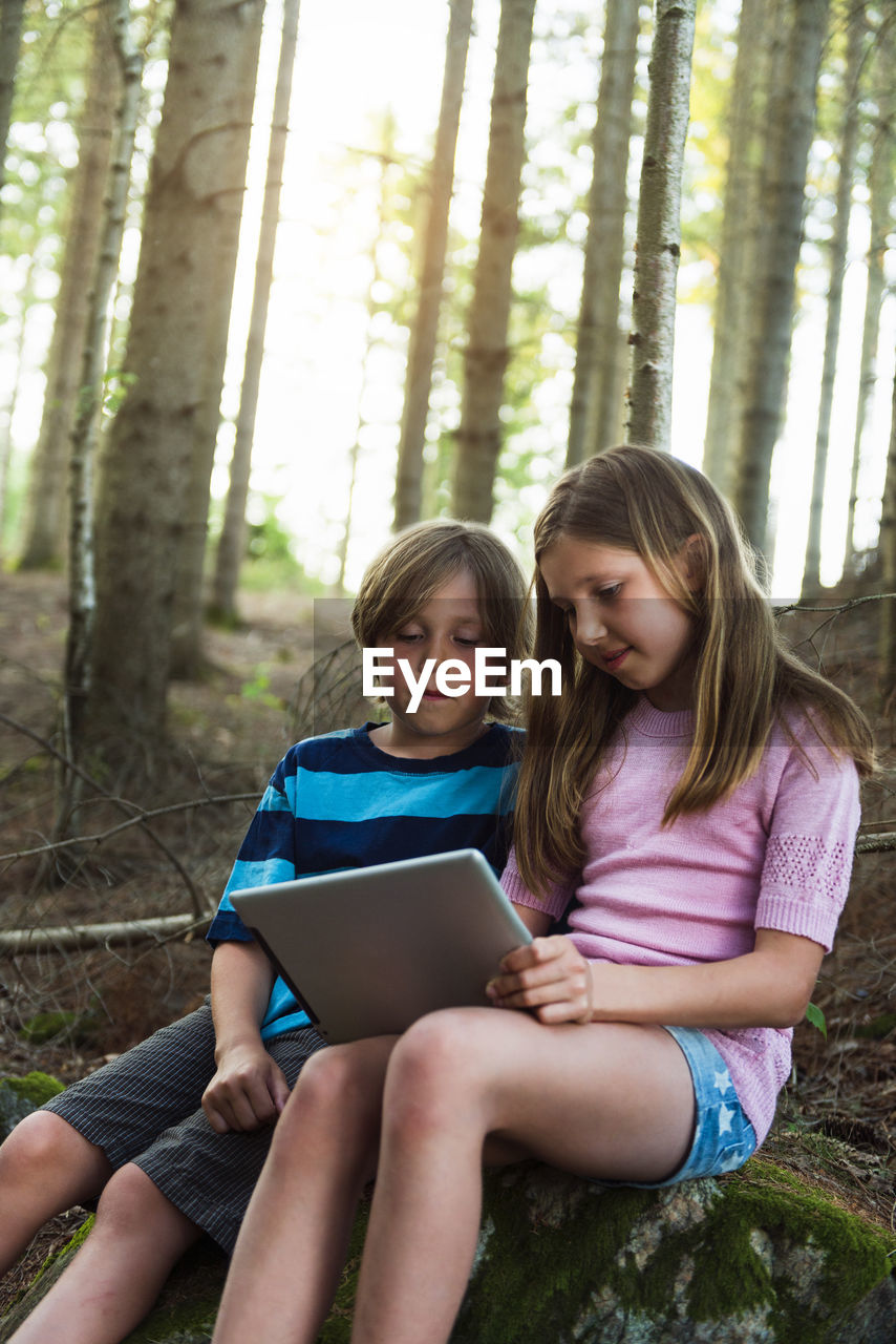 Boy and girl using digital tablet in forest