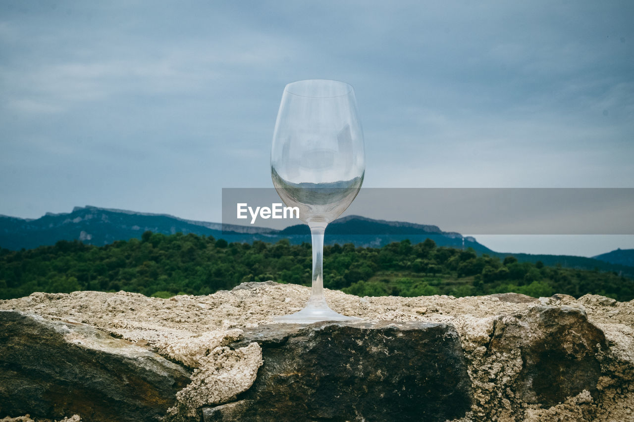 View of glass on rock against sky