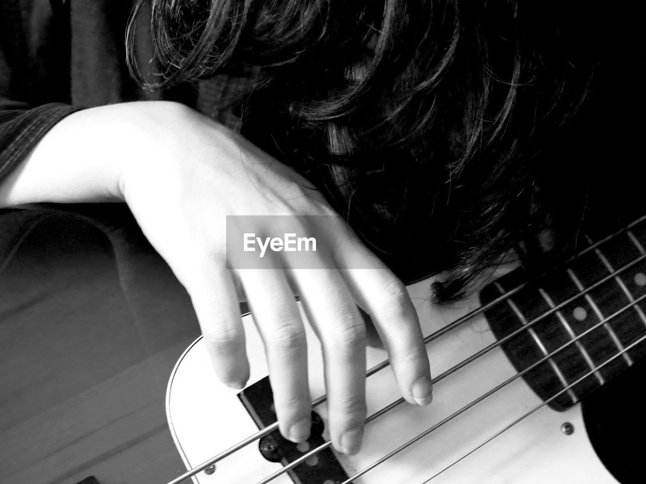MIDSECTION OF WOMAN PLAYING GUITAR AT HOME
