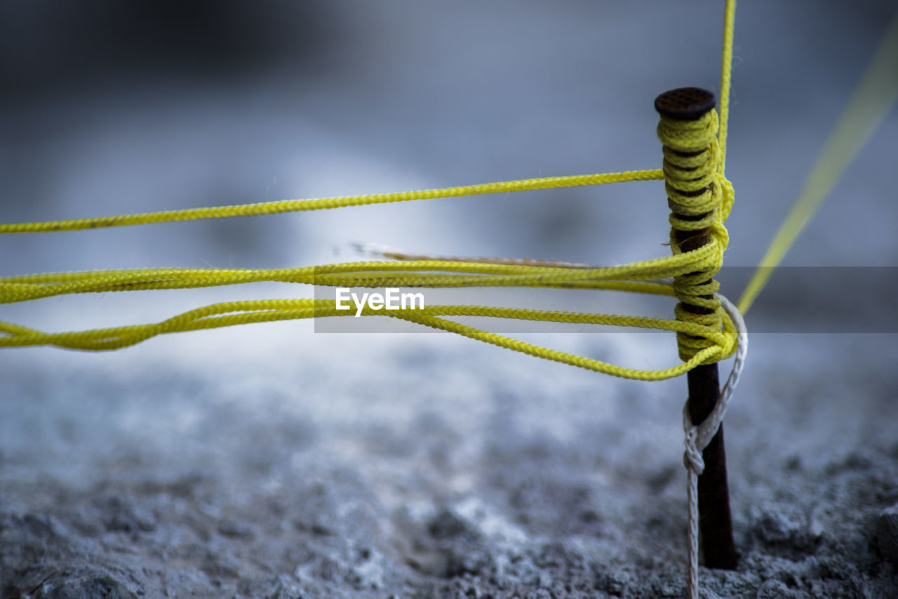 Close-up of yellow rope tied on nail