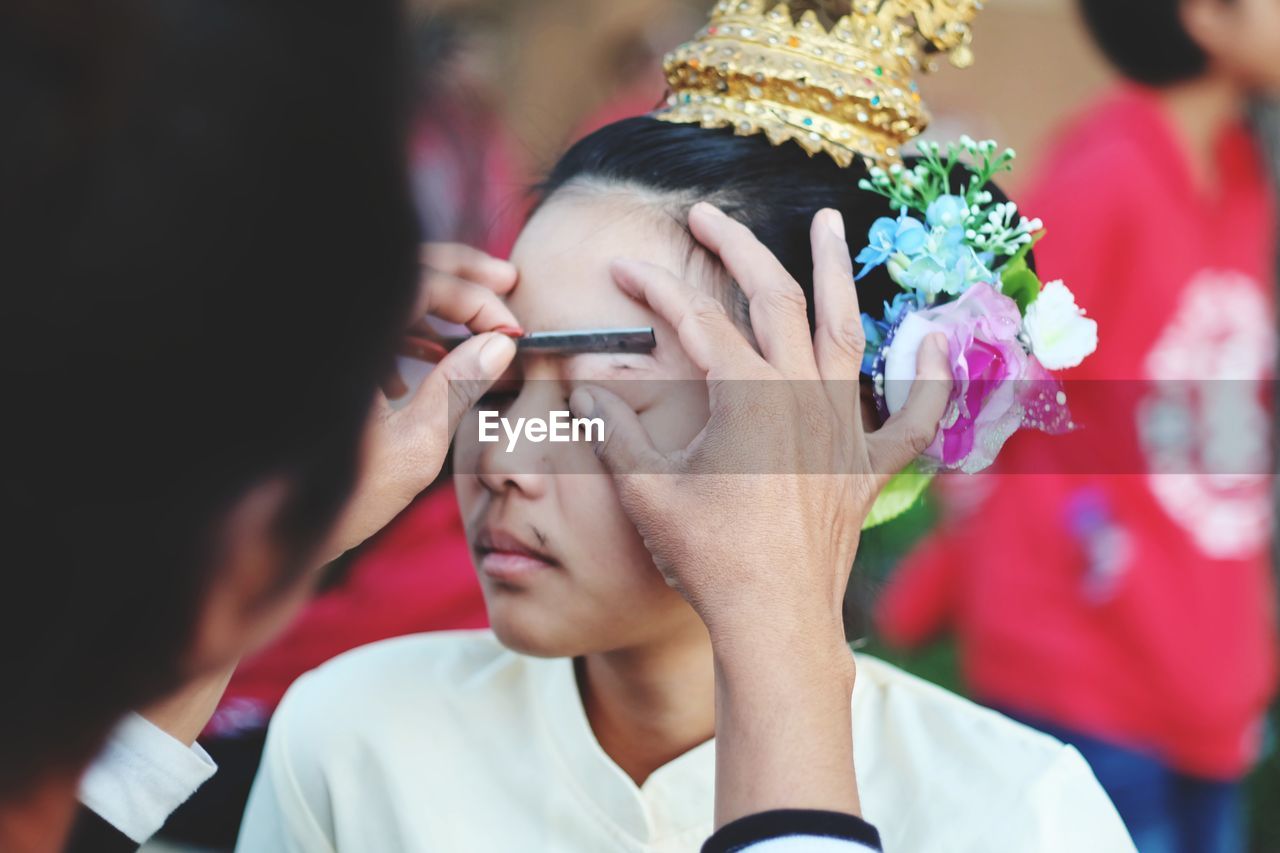 Beautician applying make-up on young woman