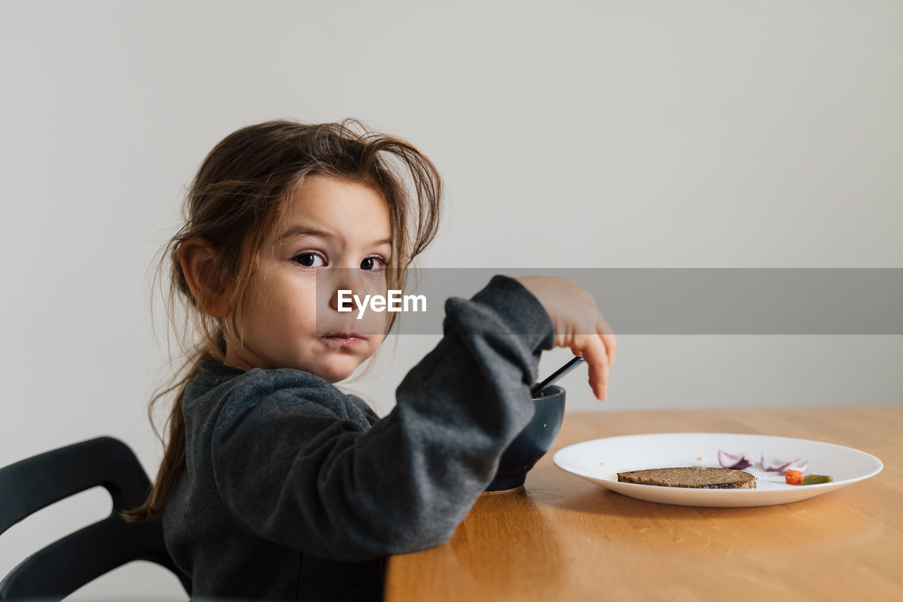 Portrait of cute girl eating food at home