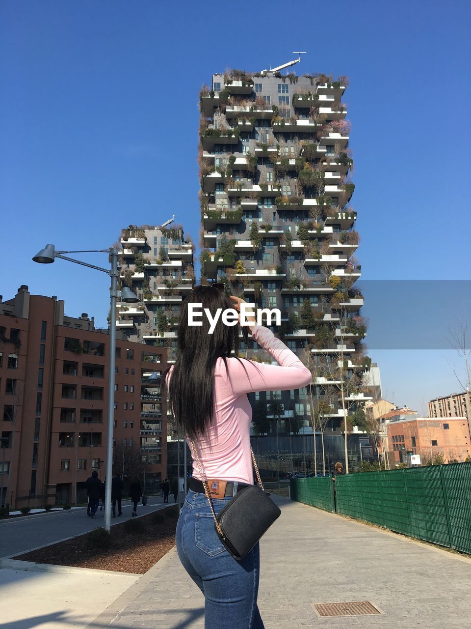 Woman looking towards buildings while standing on footpath in city