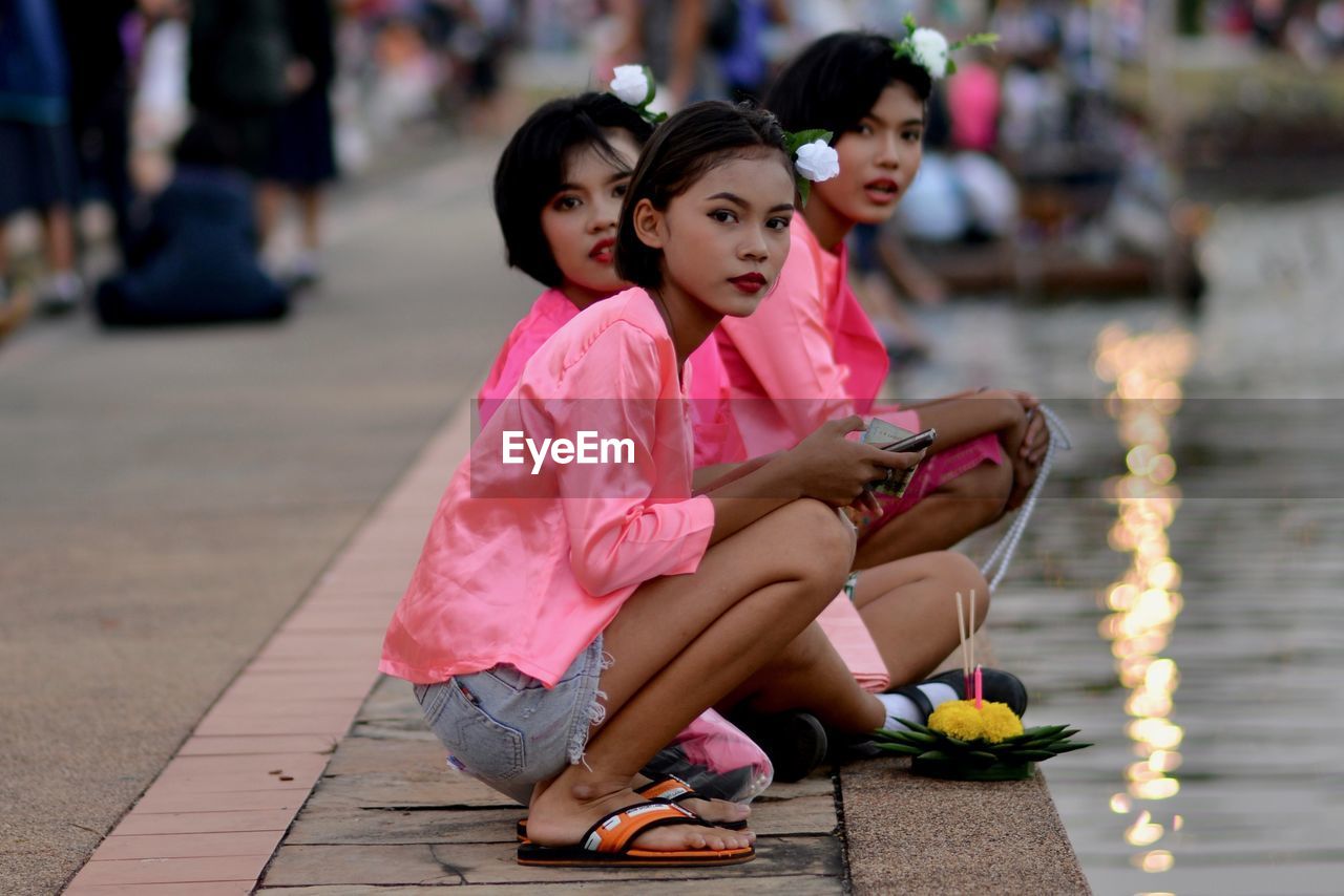 Young woman using mobile phone while sitting by lake in city