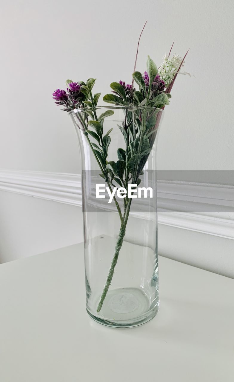 Flower vase on table against glass wall