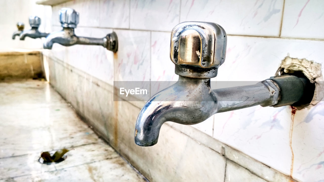 CLOSE-UP OF OLD FAUCET ON WALL IN BATHROOM