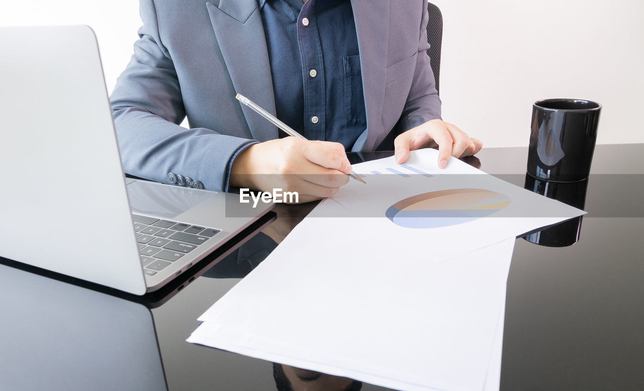 Front view of young and smart businessman manager who is working on work place desk in office 