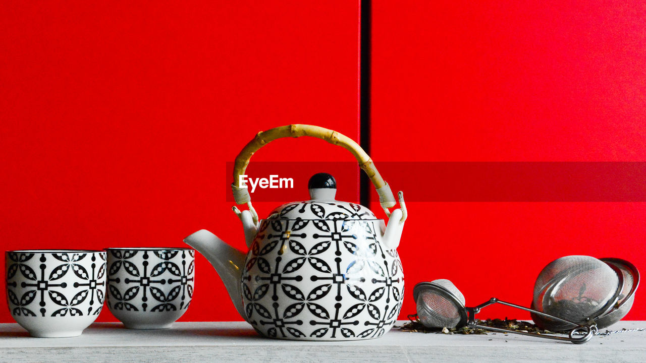 Close-up of crockery on table next to red wall