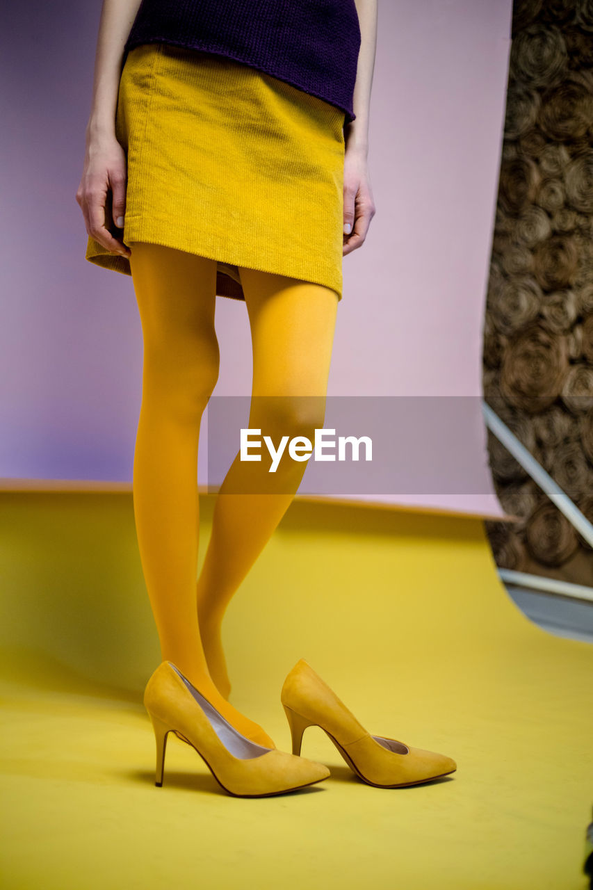 Low section of woman standing in yellow shoes