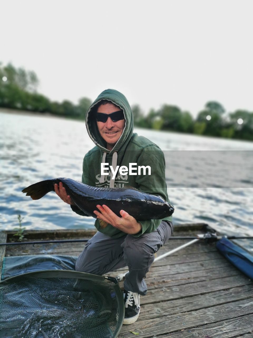 PORTRAIT OF SENIOR MAN HOLDING LAKE AGAINST SKY