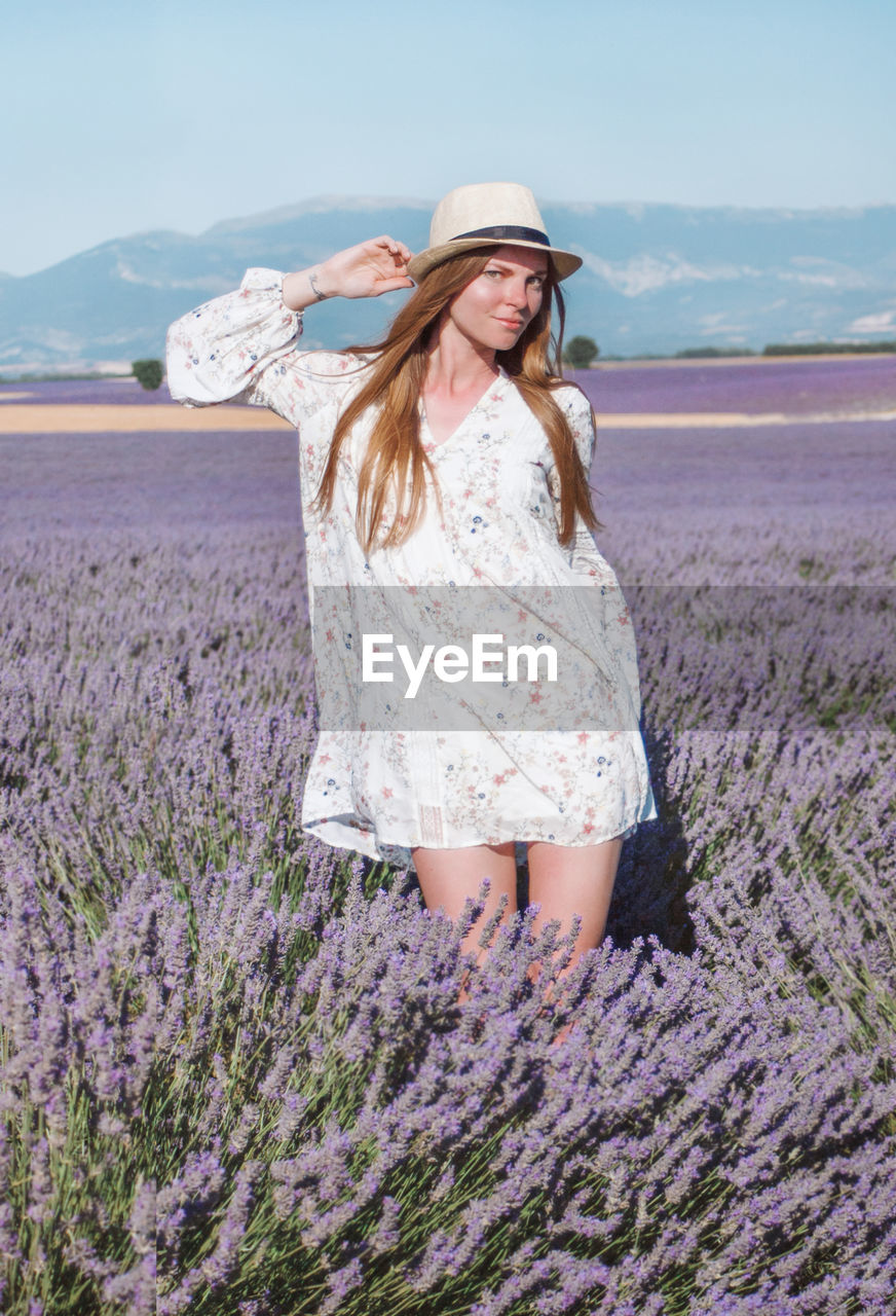 Young long hair woman in hat and dress among lavender fields in provence, france.