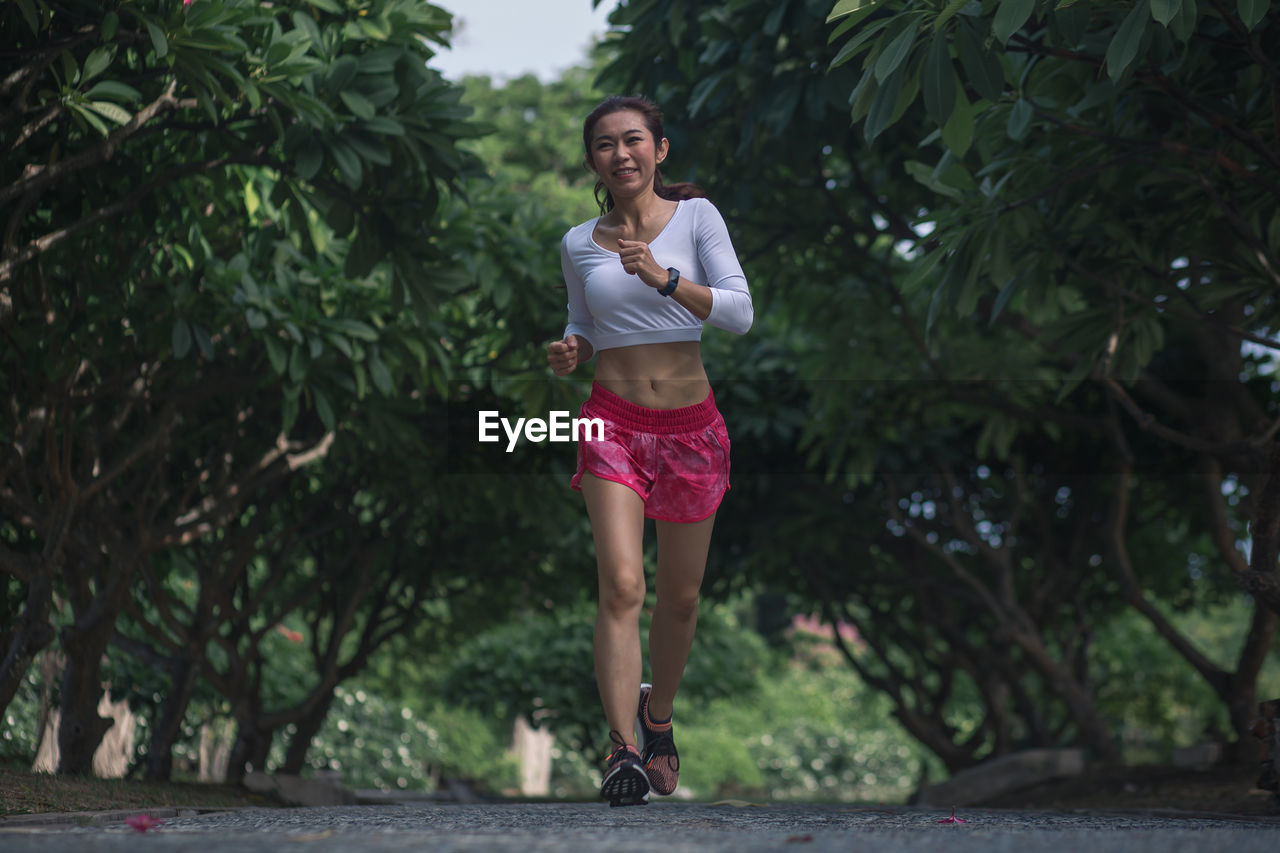 PORTRAIT OF HAPPY WOMAN AGAINST TREES