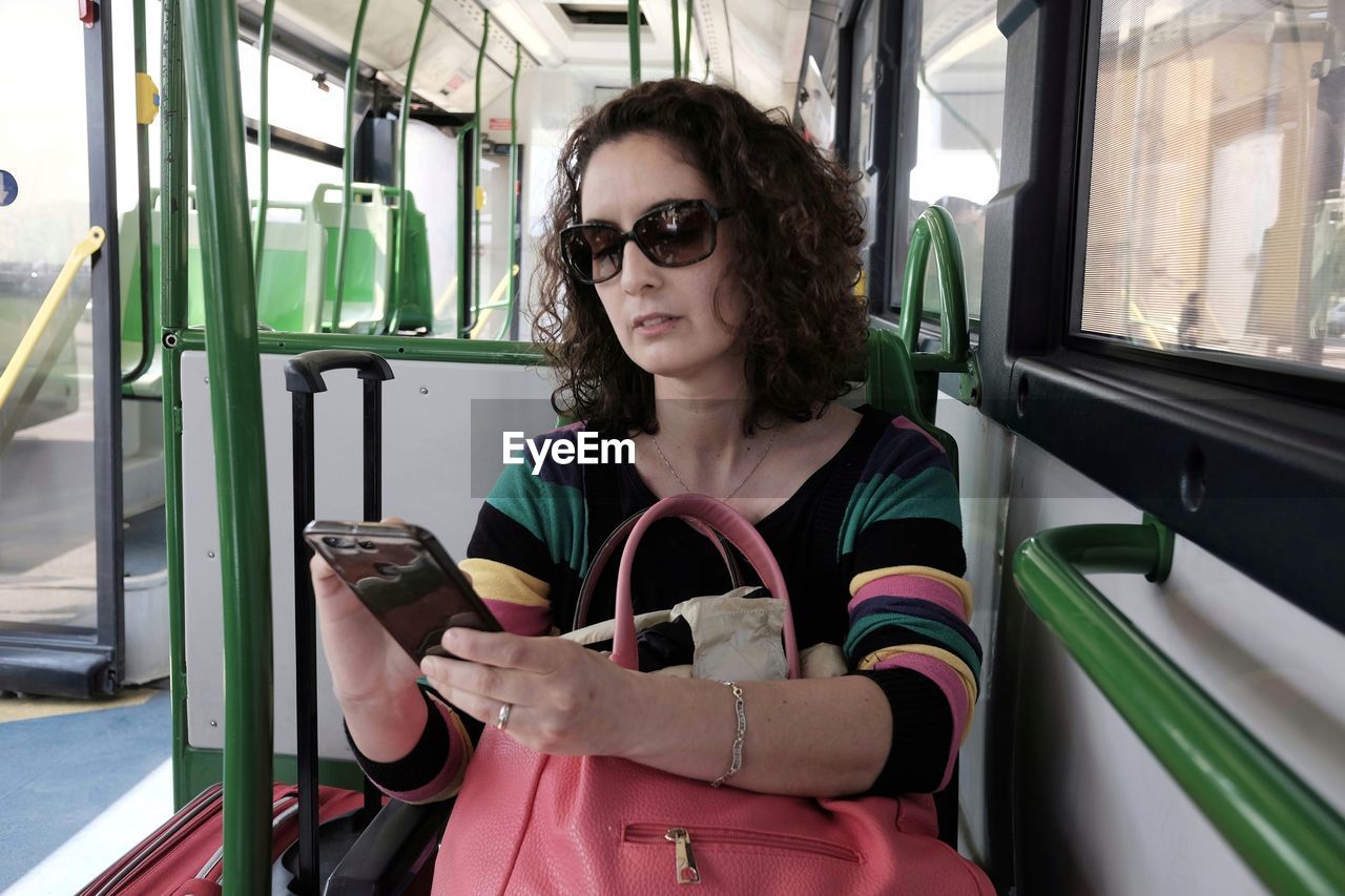 Mid adult woman using phone sitting in bus
