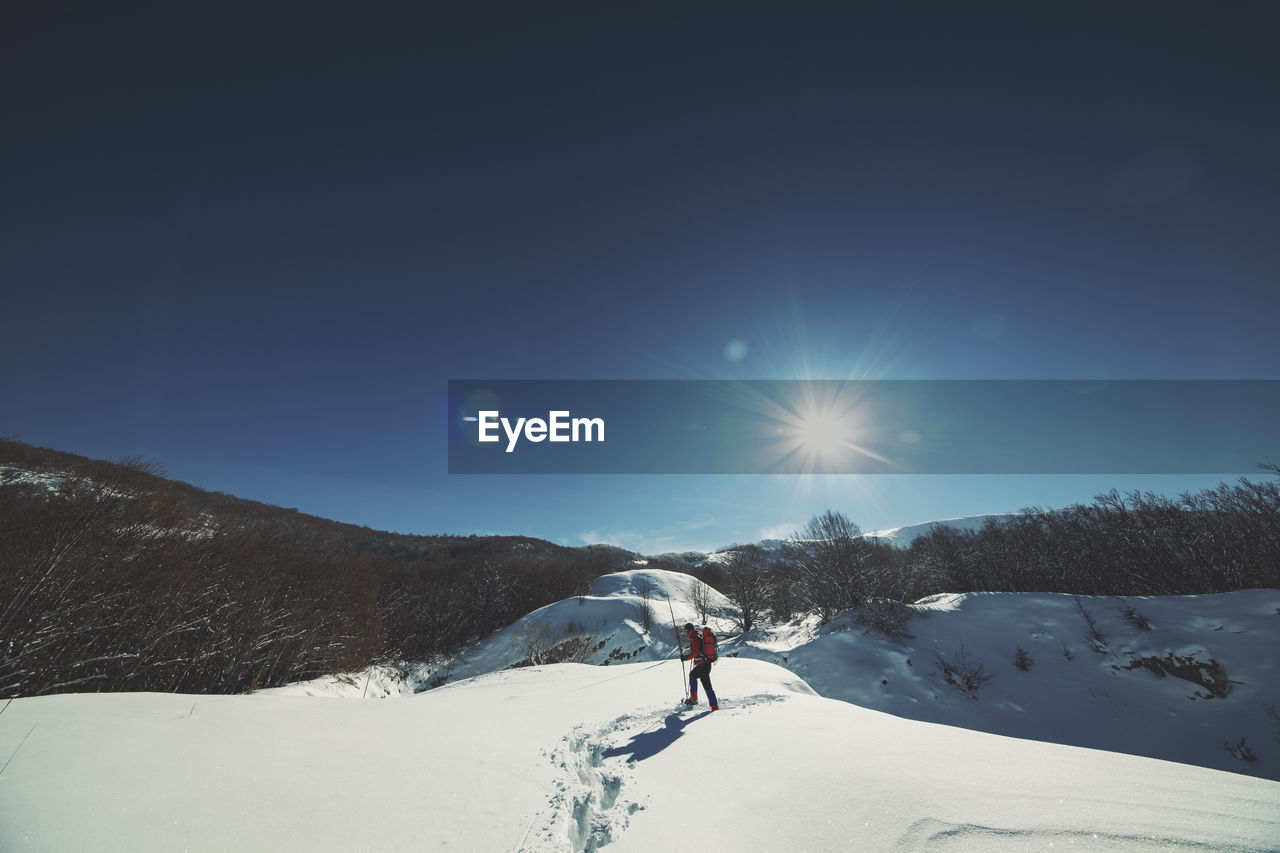 Man walking on snowcapped mountain against sky