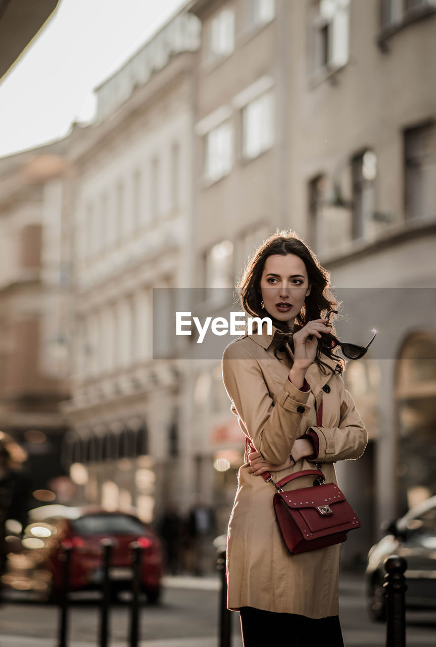 Fashionable woman standing against building in city