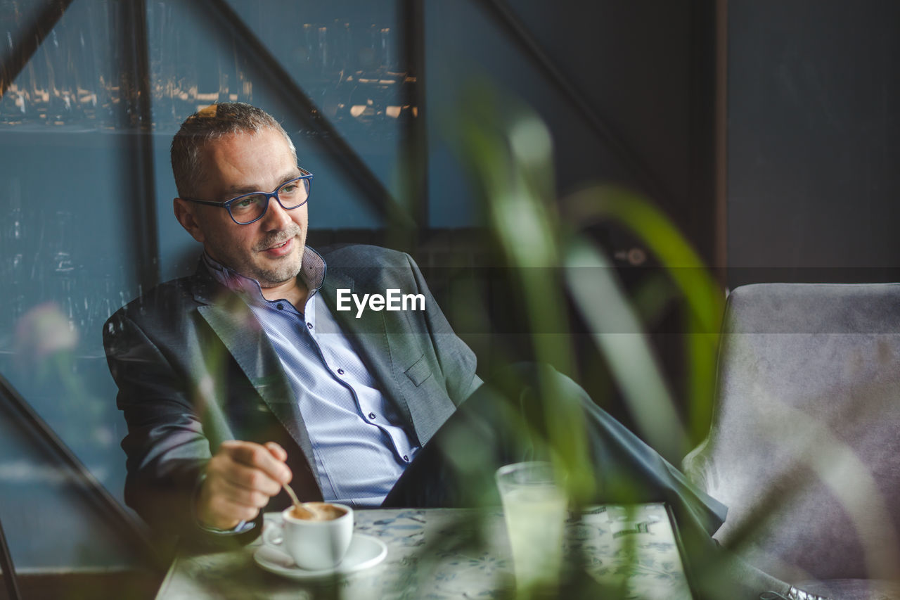 Businessman with coffee cup on table sitting in cafe