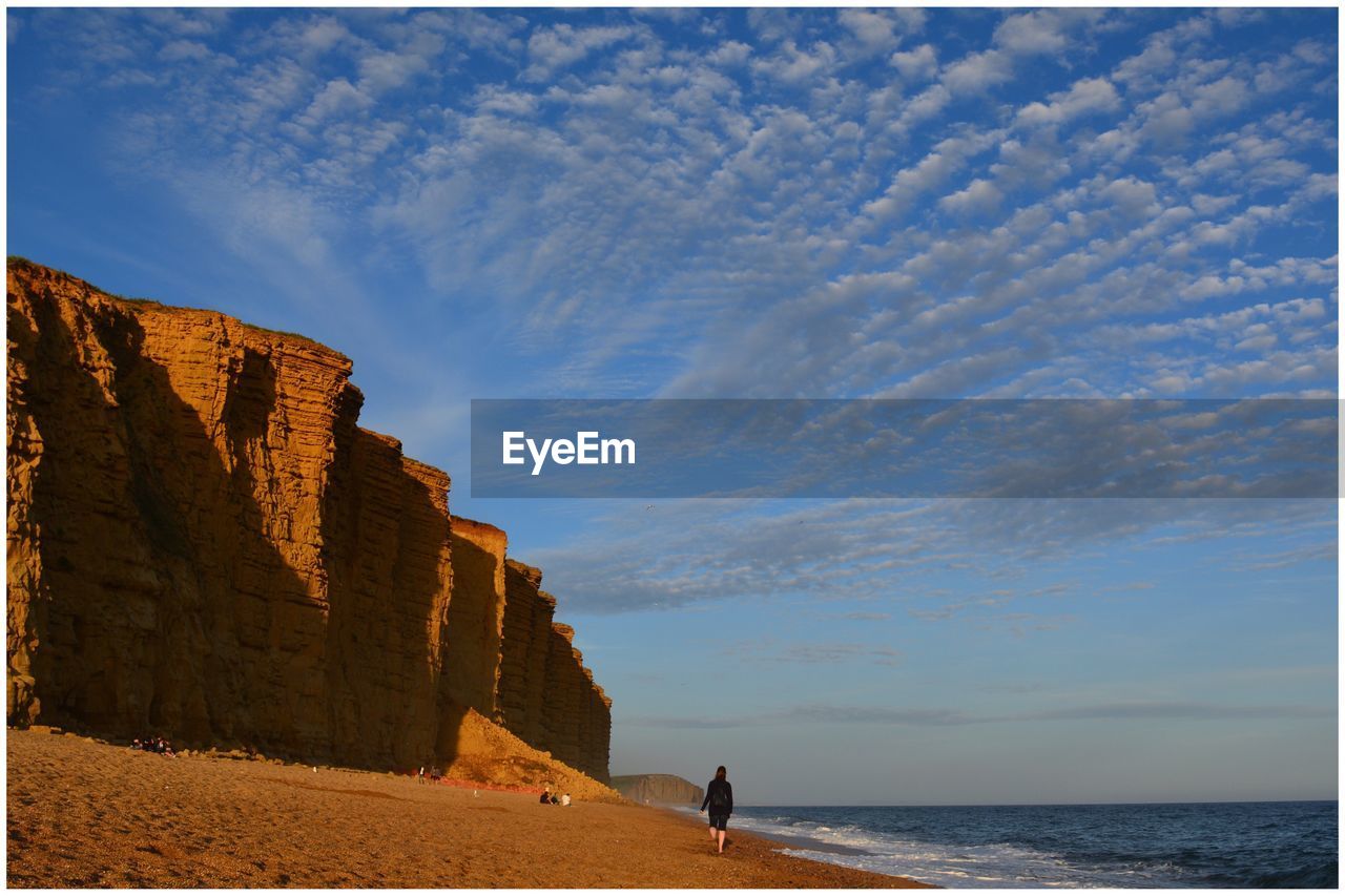 WOMAN ON BEACH AGAINST SKY