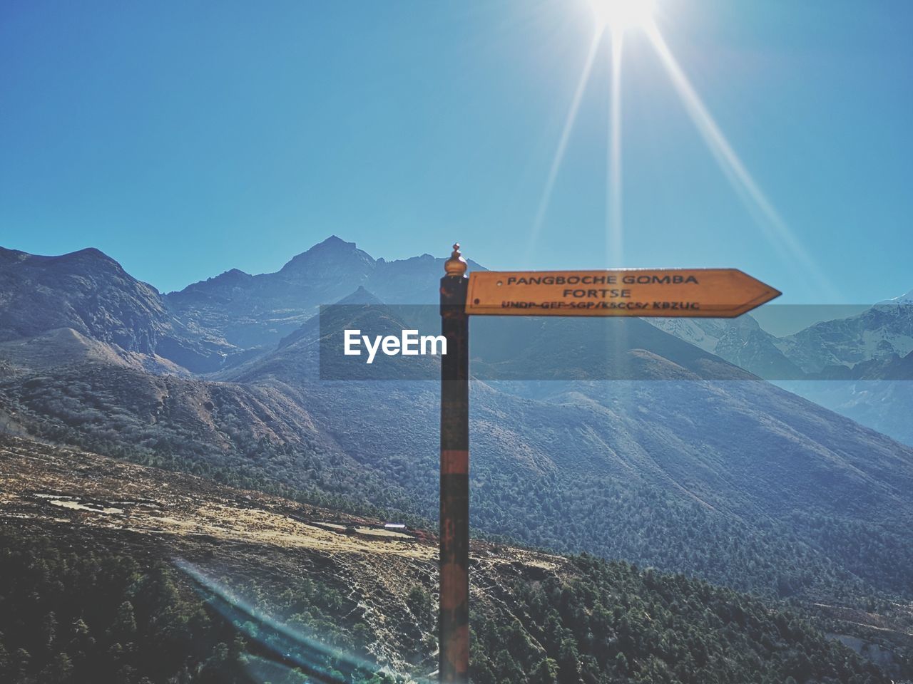 ROAD SIGN ON MOUNTAIN AGAINST BLUE SKY