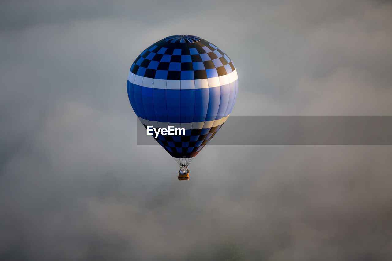 Hot air balloon flying against cloudy sky