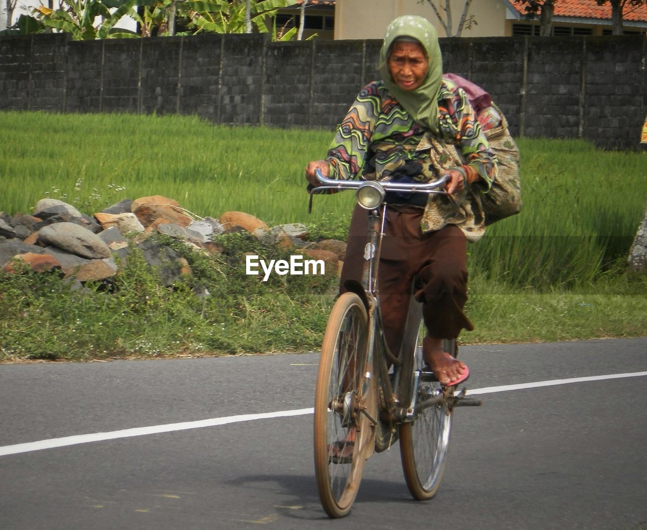 Senior woman riding bicycle on road