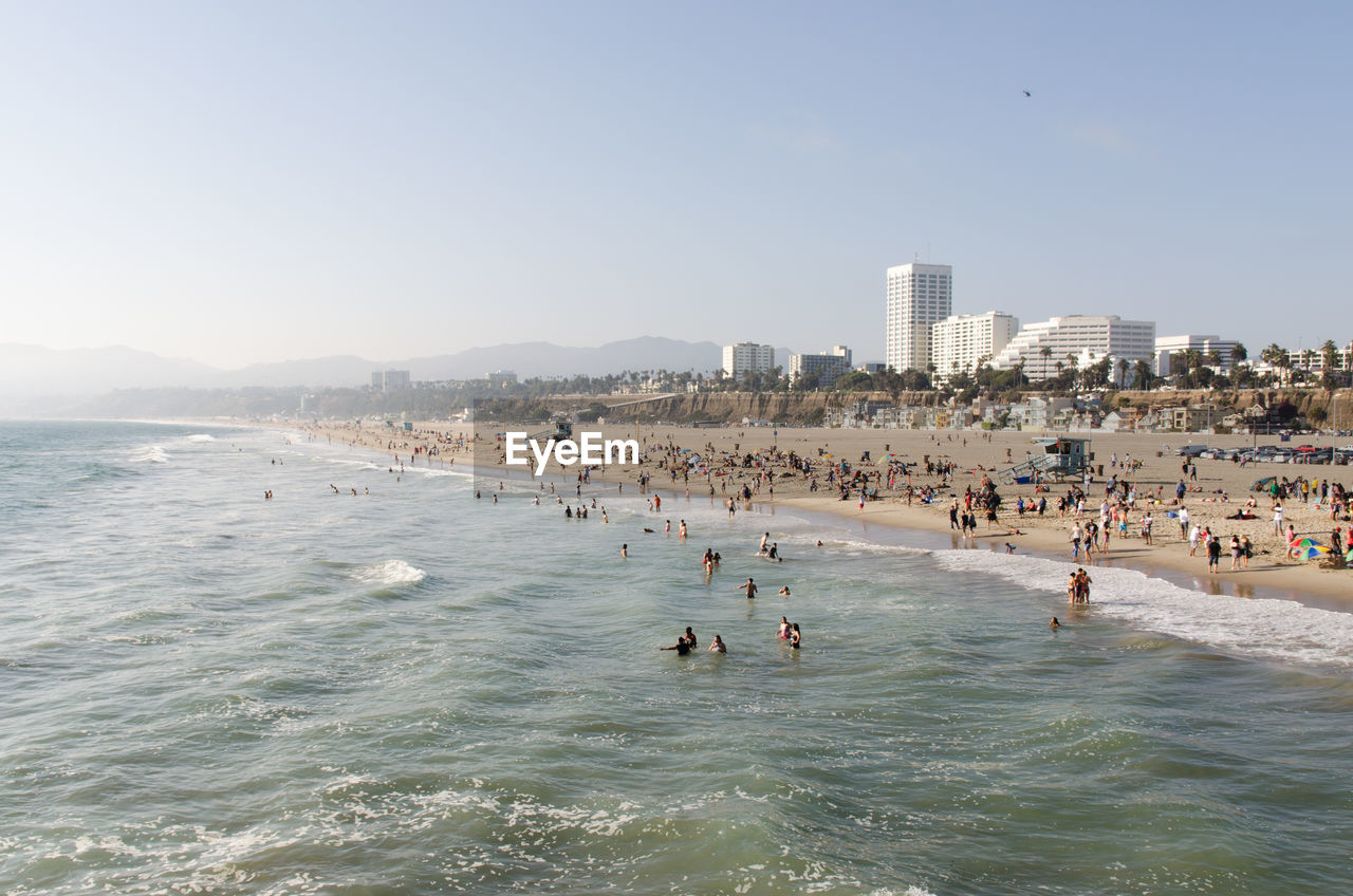 PEOPLE AT BEACH AGAINST CLEAR SKY