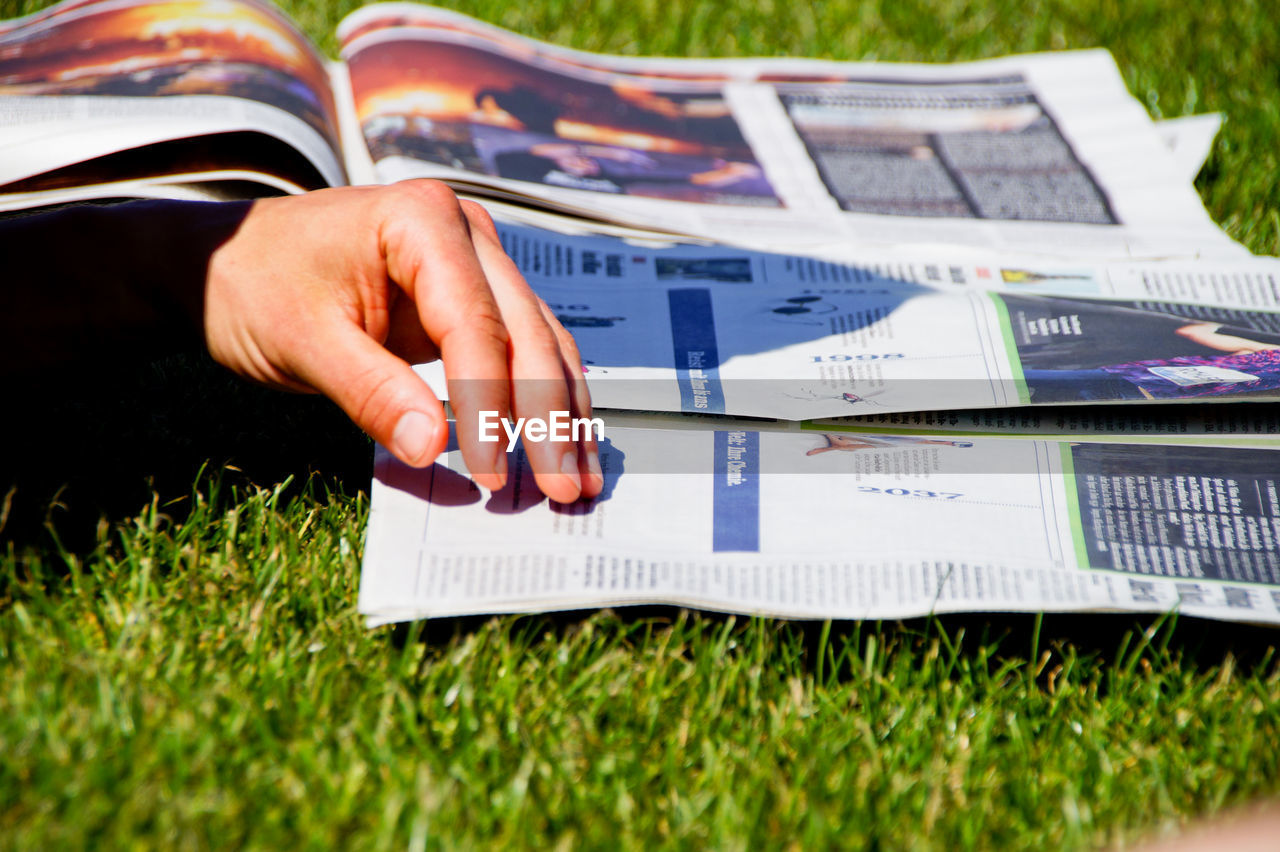 Close-up of man reading newspaper on field