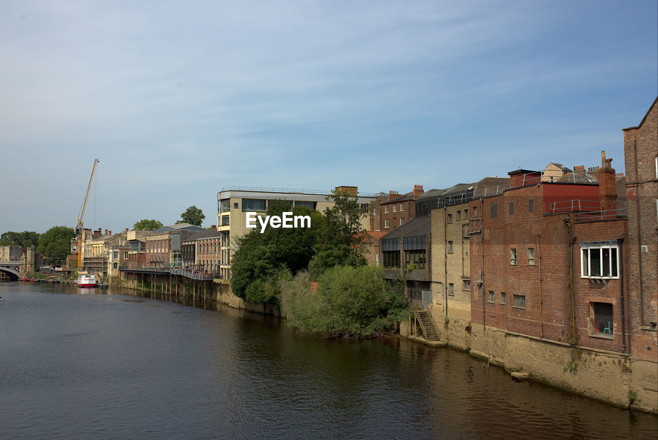 RIVER BY BUILDINGS AGAINST SKY