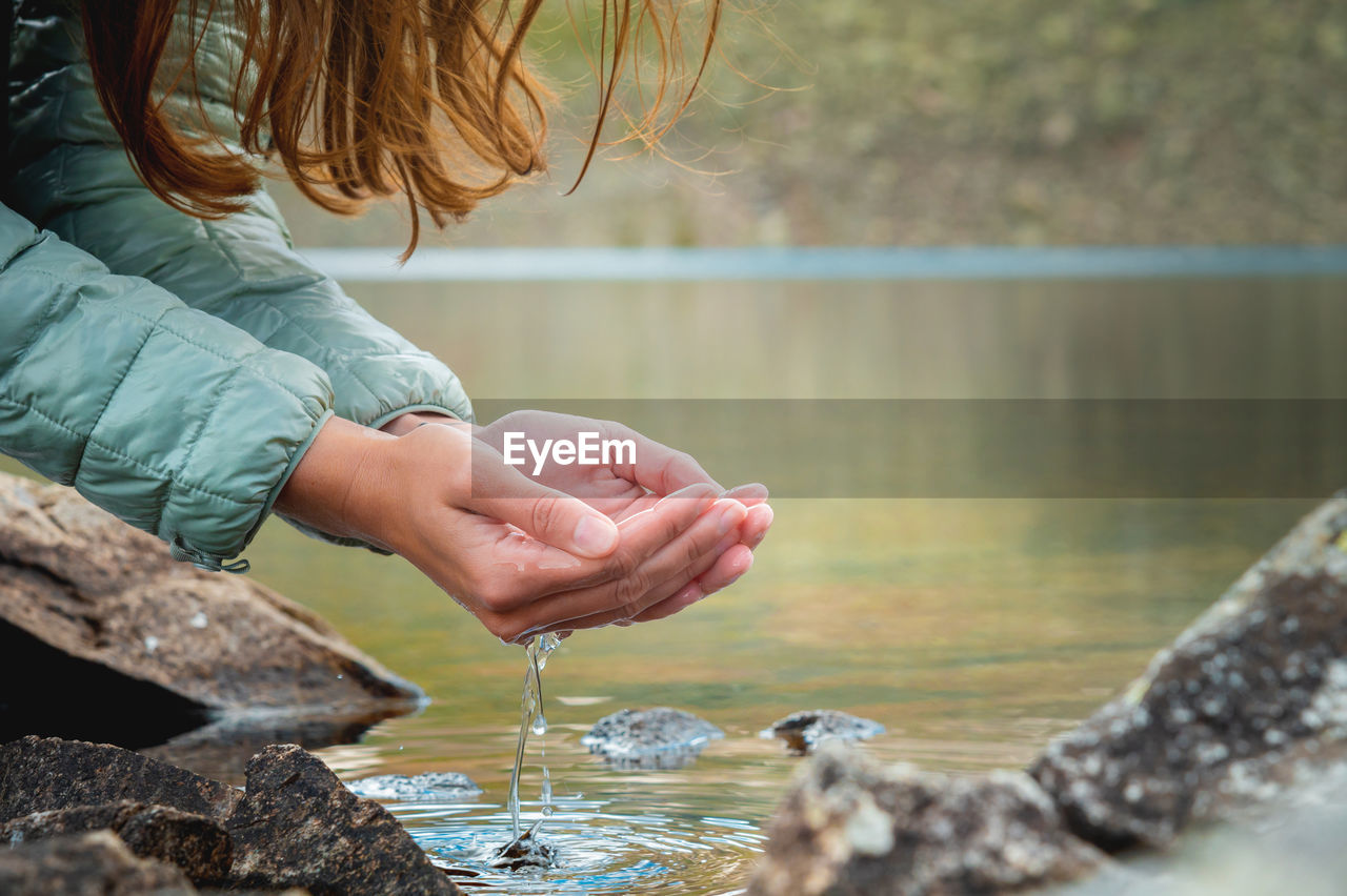 Close-up, hands of a girl drinking water from a stream or lake in the mountains. tourist quenches