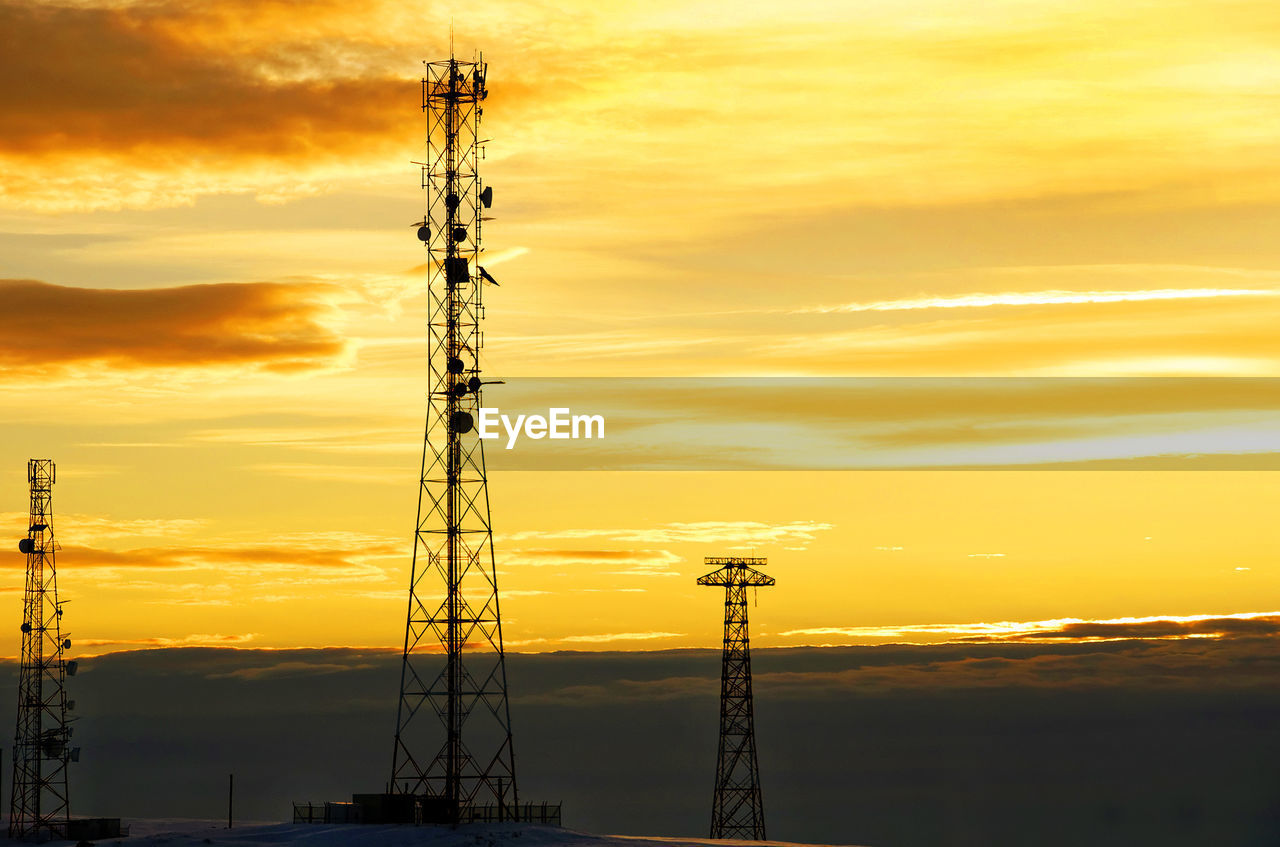 SILHOUETTE ELECTRICITY PYLONS AGAINST ORANGE SKY