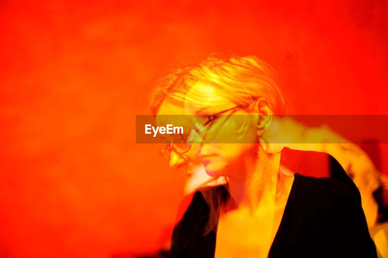 Double exposure of woman against orange background