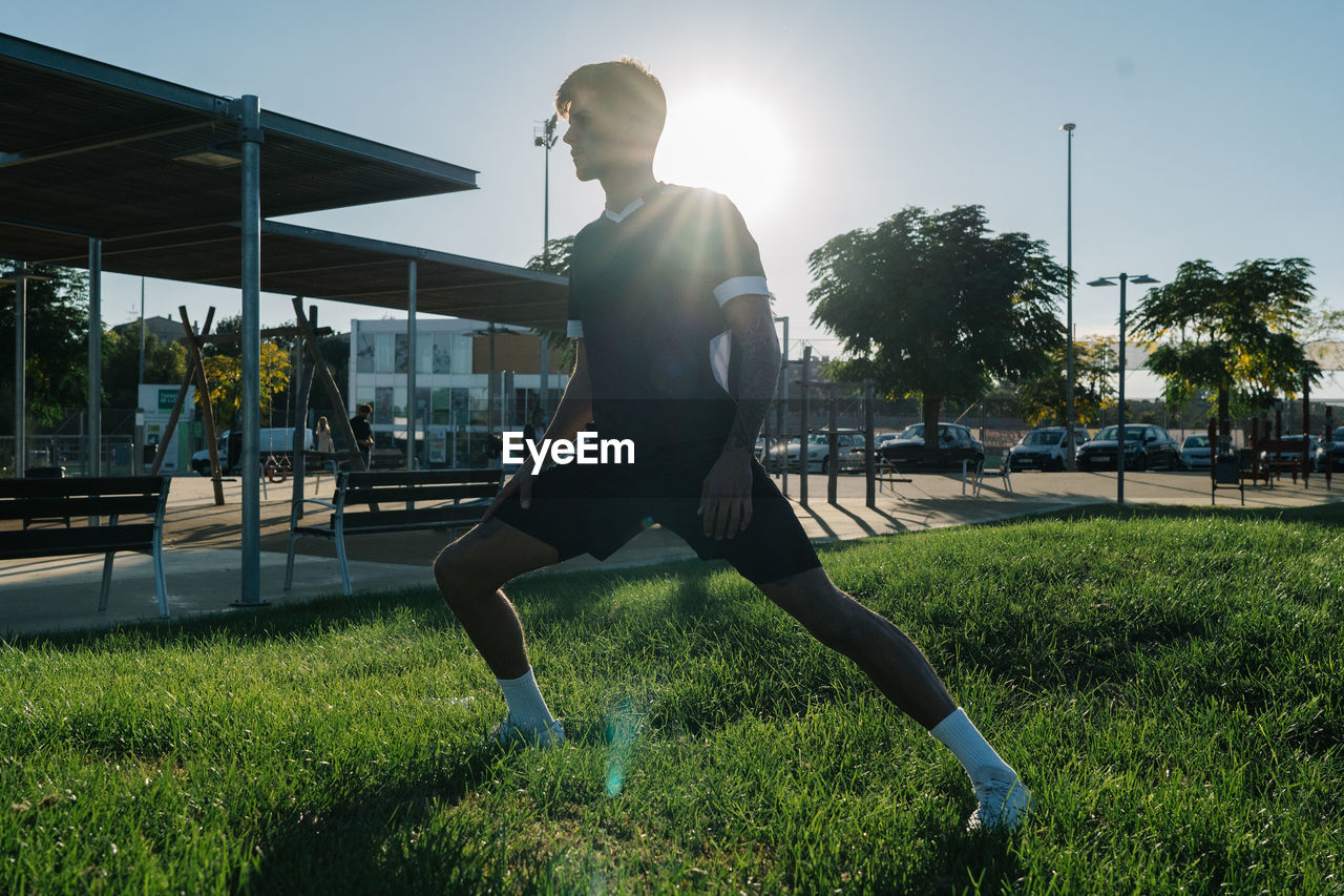 Boy stretching his legs in a park before running