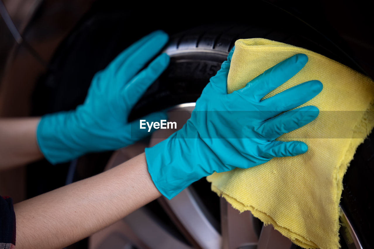 Asian women cleaning car rubber wearing green gloves with micro fibercloth yellow