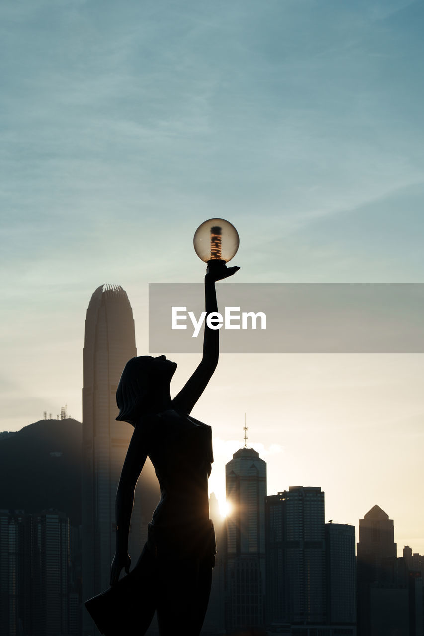 rear view of man with arms outstretched standing against sky during sunset